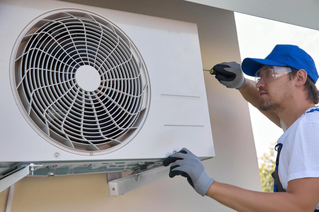 An HVAC technician installing an outside air conditioner