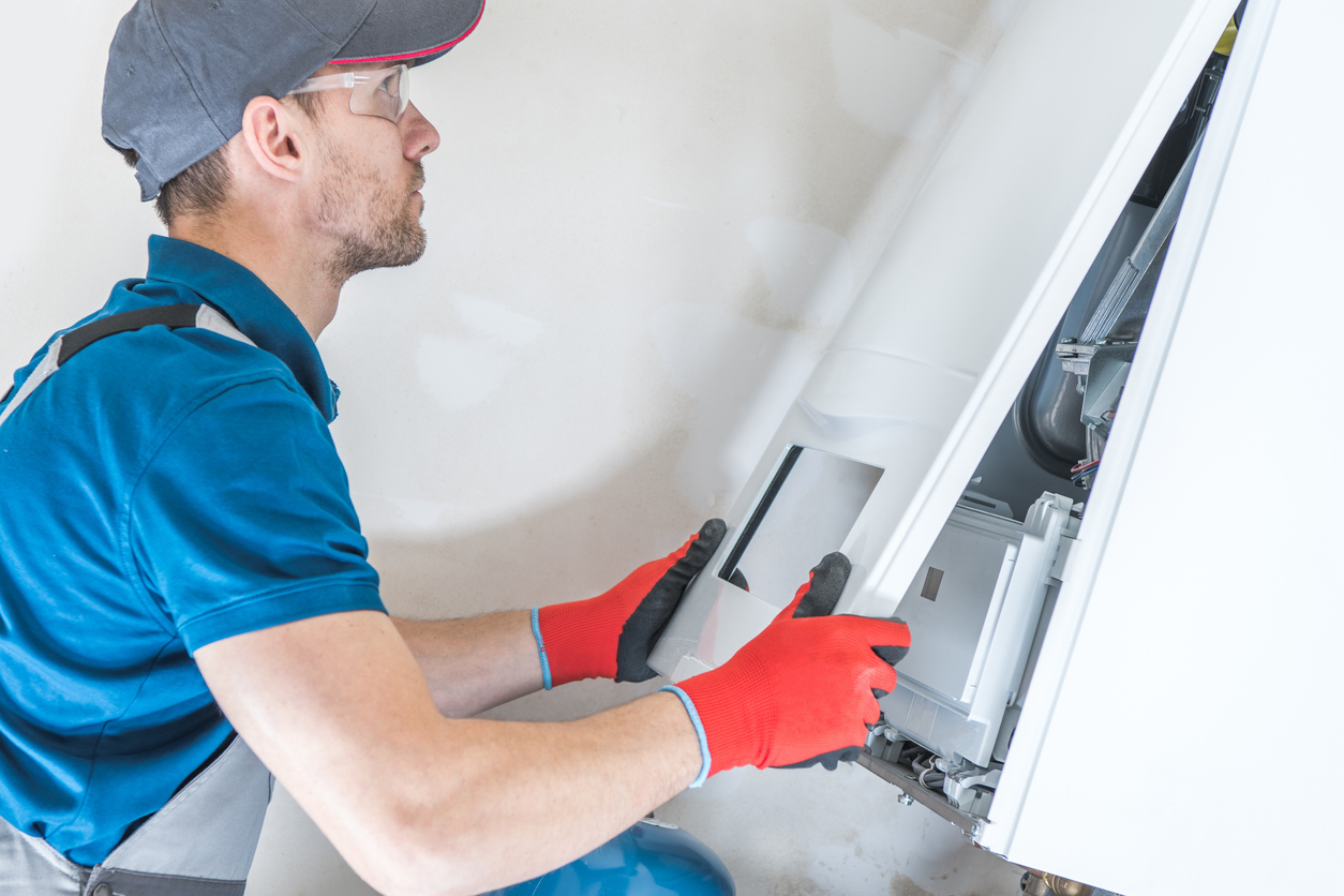 An HVAC technician installing a home furnace.