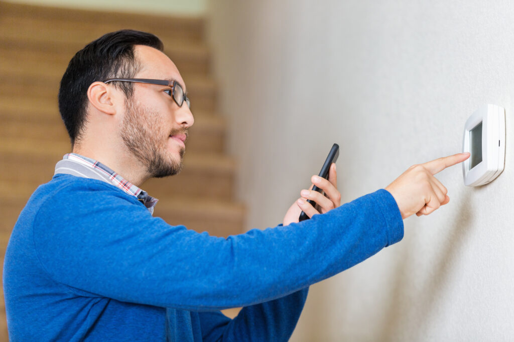 Man adjusting thermostat with smartphone app